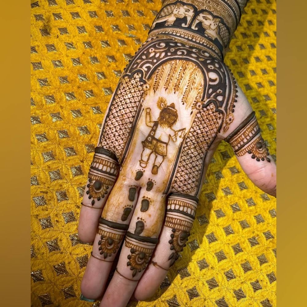 ਲੱਡੂ ਗੋਪਾਲ ਦੇ ਜਨਮਦਿਨ 'ਤੇ ਇਹ ਮਹਿੰਦੀ ਡਿਜ਼ਾਈਨ ਪਰਫੈਕਟ ਰਵੇਗਾ। ਦਿਖਾਇਆ ਗਿਆ ਹੈ ਕਿ ਸ਼੍ਰੀ ਕ੍ਰਿਸ਼ਨ ਦਾ ਆਗਮਨ ਹੋ ਚੁੱਕਿਆ ਹੈ ਅਤੇ ਉਨ੍ਹਾਂ ਦੇ ਪੈਰਾਂ ਦੇ ਨਿਸ਼ਾਨ ਵੀ ਦਿਖਾਏ ਗਏ ਹਨ। ਇਸ ਦੇ ਆਲੇ-ਦੁਆਲੇ ਬਹੁਤ ਹੀ ਵਧੀਆ ਜਾਲੀਦਾਰ ਡਿਜ਼ਾਈਨਾਂ ਨਾਲ ਸਜਾਈ ਗਾਂ ਹੈ। ਇਸ ਤੋਂ ਇਲਾਵਾ ਇਸ ਵਿਚ ਹਾਥੀ ਦੀ ਤਸਵੀਰ ਵੀ ਬਣਾਈ ਗਈ ਹੈ। ( Credit : nirali_mehndiii )