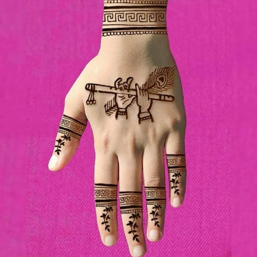 ਮਹਿੰਦੀ ਦਾ ਇਹ ਡਿਜ਼ਾਈਨ ਬਹੁਤ ਹੀ ਸਿਪੰਲ ਹੈ ਅਤੇ ਇਸ ਨੂੰ ਲਗਾਉਣਾ ਬਹੁਤ ਆਸਾਨ ਹੈ। ਇਸ ਵਿੱਚ ਭਗਵਾਨ ਕ੍ਰਿਸ਼ਨ ਦੇ ਹੱਥ ਵਿੱਚ ਇੱਕ ਬੰਸਰੀ ਅਤੇ ਮੋਰ ਦਾ ਖੰਭ ਦਿਖਾਇਆ ਗਿਆ ਹੈ। ਤੁਸੀਂ ਵੀ ਜਨਮ ਅਸ਼ਟਮੀ ਦੇ ਮੌਕੇ 'ਤੇ ਇਸ ਤਰ੍ਹਾਂ ਦੀ ਬੰਸਰੀ, ਮੋਰ ਦੇ ਖੰਭ ਅਤੇ ਮਟਕੀ ਸਟਾਈਲ ਦੇ ਡਿਜ਼ਾਈਨ ਲਗਵਾ ਸਕਦੇ ਹੋ। ( Credit : simplemehndidesign )