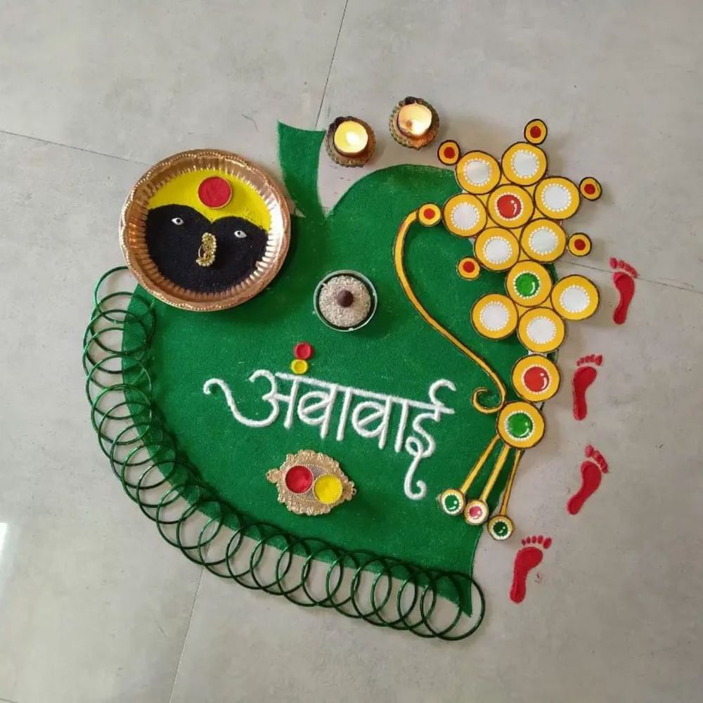 ਨਵਰਾਤਰੀ ਲਈ ਰੰਗੋਲੀ ਦਾ ਇਹ ਡਿਜ਼ਾਈਨ ਵੀ ਬਹੁਤ ਸੁੰਦਰ ਅਤੇ ਬਣਾਉਣਾ ਆਸਾਨ ਹੈ। ਇਸ ਵਿਚ ਰੰਗਾਂ ਨਾਲ ਪੱਤੇ ਦਾ ਆਕਾਰ ਬਣਾ ਕੇ ਇਸ ਦੇ ਦੁਆਲੇ ਪੈਰਾਂ ਦੇ ਨਿਸ਼ਾਨ ਬਣਾਏ ਗਏ ਹਨ ਅਤੇ ਅੰਦਰ ਅੰਬਾਬਾਈ ਲਿਖਿਆ ਗਿਆ ਹੈ। ਨਾਲ ਹੀ ਇਸ ਦੇ ਆਲੇ-ਦੁਆਲੇ ਚੂੜੀਆਂ ਲਗਾ ਕੇ ਇਸ ਨੂੰ ਖਾਸ ਬਣਾਇਆ ਗਿਆ ਹੈ। ਇਸ ਤੋਂ ਇਲਾਵਾ ਇੱਕ ਥਾਲੀ ਵਿੱਚ ਅੰਬੇ ਮਾਂ ਦਾ ਕੋਮਲ ਰੂਪ ਬਣਾਇਆ ਗਿਆ ਹੈ। ( Credit : prajuu_s_art_world )