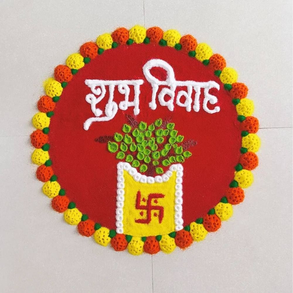 ਤੁਸੀਂ ਰੰਗੋਲੀ ਦੇ ਇਸ ਡਿਜ਼ਾਈਨ ਤੋਂ ਵੀ ਵਿਚਾਰ ਲੈ ਸਕਦੇ ਹੋ। ਇਸ ਵਿੱਚ ਲਾਲ ਰੰਗ ਦੇ ਨਾਲ ਇੱਕ ਚੱਕਰ ਦਾ ਆਕਾਰ ਬਣਾ ਕੇ ਇਸ ਵਿੱਚ ਤੁਲਸੀ ਦਾ ਬੂਟਾ ਲਗਾਇਆ ਗਿਆ ਹੈ। ਇਹ ਵੀ ਲਿਖਿਆ ਹੈ ਕਿ ਇਹ ਸ਼ੁਭ ਵਿਆਹ ਹੈ। ਆਲੇ-ਦੁਆਲੇ ਦੇ ਡਿਜ਼ਾਈਨ ਨੂੰ ਹਰੇ, ਪੀਲੇ ਅਤੇ ਸੰਤਰੀ ਰੰਗਾਂ ਵਿੱਚ ਬਣਾਇਆ ਗਿਆ ਹੈ।( Credit : shikha_creation17 )