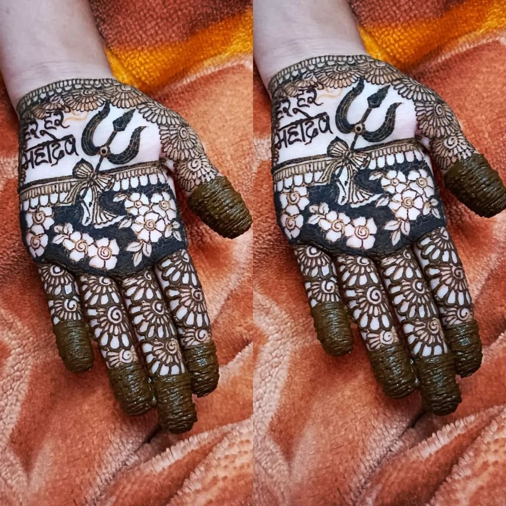 ਜੇਕਰ ਤੁਸੀਂ ਆਪਣੇ ਪੂਰੇ ਹੱਥਾਂ 'ਤੇ ਮਹਿੰਦੀ ਲਗਾਉਣਾ ਚਾਹੁੰਦੇ ਹੋ ਤਾਂ ਤੁਸੀਂ ਇਸ ਡਿਜ਼ਾਈਨ ਤੋਂ ਆਈਡੀਆ ਲੈ ਸਕਦੇ ਹੋ। ਇਸ ਉੱਤੇ ਹਰ ਹਰ ਮਹਾਦੇਵ ਲਿਖਿਆ ਹੋਇਆ ਹੈ, ਅਤੇ ਇਸ ਉੱਤੇ ਭਗਵਾਨ ਸ਼ਿਵ ਦਾ ਤ੍ਰਿਸ਼ੂਲ ਅਤੇ ਡਮਰੂ ਬਣਾਏ ਗਏ ਹਨ। ਨਾਲ ਹੀ, ਇਸਦੇ ਆਲੇ-ਦੁਆਲੇ ਫੁੱਲਾਂ ਦਾ ਡਿਜ਼ਾਈਨ ਬਣਾਇਆ ਗਿਆ ਹੈ। ਇਹ ਮਹਿੰਦੀ ਡਿਜ਼ਾਈਨ ਵੀ ਬਹੁਤ ਸਰਲ ਹੈ, ਜਿਸਨੂੰ ਘਰ ਵਿੱਚ ਲਗਾਇਆ ਜਾ ਸਕਦਾ ਹੈ। ( Credit : sona_nails_mehendi )