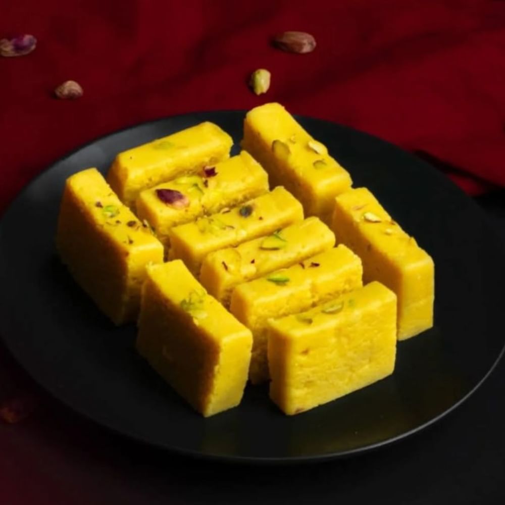ਹੁਣ ਮਾਵੇ ਨੂੰ ਕੱਢ ਕੇ ਉਸੇ ਪੈਨ ਵਿੱਚ ਅੰਬ ਦਾ ਗੁੱਦਾ ਪਾਓ ਅਤੇ ਇਸਨੂੰ ਉਦੋਂ ਤੱਕ ਭੁੰਨੋ ਜਦੋਂ ਤੱਕ ਸਾਰਾ ਪਾਣੀ ਸੁੱਕ ਨਾ ਜਾਵੇ ਅਤੇ ਇਹ ਗਾੜ੍ਹਾ ਨਾ ਹੋ ਜਾਵੇ। ਜਦੋਂ ਅੰਬ ਗਾੜ੍ਹਾ ਹੋ ਜਾਵੇ ਤਾਂ ਇਸ ਵਿੱਚ ਖੰਡ ਪਾਓ ਅਤੇ ਮਾਵੇ ਨੂੰ ਭੁੰਨੋ। ਜਦੋਂ ਇਹ ਮਿਸ਼ਰਣ ਪੈਨ ਦੇ ਕਿਨਾਰਿਆਂ ਤੋਂ ਨਿਕਲ ਜਾਵੇ ਤਾਂ ਇਸ ਵਿੱਚ ਇਲਾਇਚੀ ਪਾਊਡਰ ਪਾਓ ਅਤੇ ਗੈਸ ਬੰਦ ਕਰ ਦਿਓ। (Credit:ali_mithai_f.t.s)