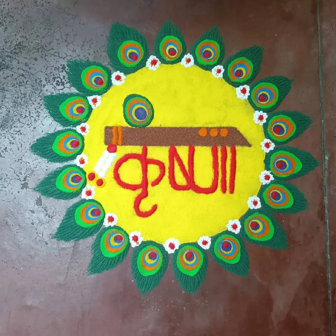 ਰੰਗੋਲੀ ਦਾ ਇਹ ਡਿਜ਼ਾਈਨ ਵੀ ਤੁਸੀਂ ਘਰ ਬਣਾ ਸਕਦੇ ਹੋ। ਇਸ ਵਿੱਚ ਪੀਲੇ ਰੰਗ ਨਾਲ ਇੱਕ ਗੋਲਾ ਬਣਾਇਆ ਜਾਂਦਾ ਹੈ ਅਤੇ ਅੰਦਰ ਕ੍ਰਿਸ਼ਨਾ ਲਿਖਿਆ ਹੈ ਅਤੇ ਇੱਕ ਬੰਸਰੀ ਬਣਾਈ ਹੈ। ਇਸ ਦੇ ਆਲੇ-ਦੁਆਲੇ ਮੋਰ ਦੇ ਖੰਭ ਦਾ ਡਿਜ਼ਾਈਨ ਵੀ ਬਣਾਇਆ ਜਾਂਦਾ ਹੈ। ਇਸਨੂੰ ਬਣਾਉਣਾ ਵੀ ਆਸਾਨ ਹੋਵੇਗਾ। ( Credit : ranupriya_mansingh )