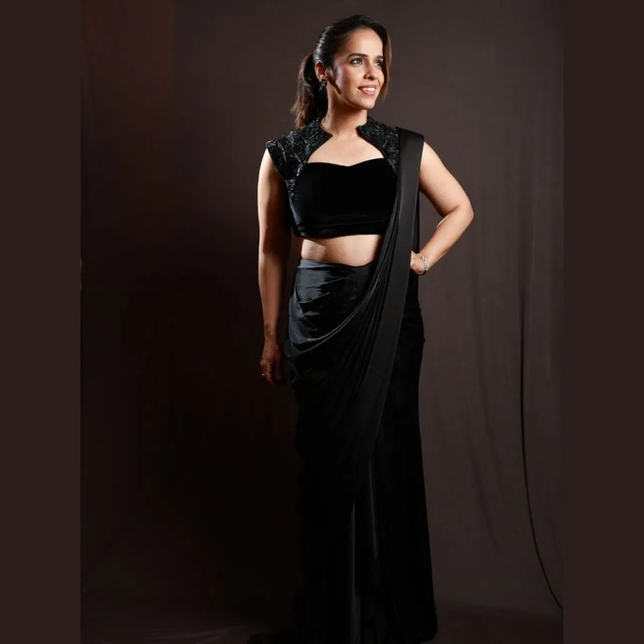 ਇਸ ਬਲੈਕ ਸਾੜੀ ਵਿੱਚ ਸਾਇਨਾ ਬਹੁਤ ਗਲੈਮਰਸ ਅਤੇ ਸਟਨਿੰਗ ਲੱਗ ਰਹੀ ਹੈ। ਪਲੇਨ ਸਾੜੀ ਵਾਲਾ ਇਹ ਡਿਜ਼ਾਈਨਰ ਬਲਾਊਜ਼ ਉਨ੍ਹਾਂ ਦੇ ਲੁੱਕ ਵਿੱਚ ਗਲੈਮਰ ਐਡ ਕਰ ਰਿਹਾ ਹੈ। ਗਲੋਇੰਗ ਮੇਕਅਪ, ਸਾੜੀ ਦਾ ਡਰੈਪਿੰਗ ਸਟਾਈਲ ਅਤੇ ਸਿੰਪਲ ਹੇਅਰ ਸਟਾਈਲ ਦੇ ਨਾਲ, ਉਨ੍ਹਾਂ ਦਾ ਇਹ ਲੁੱਕ ਐਲੀਗੈਂਸ ਅਤੇ ਗ੍ਰੇਸਫੁੱਲ ਹੈ।