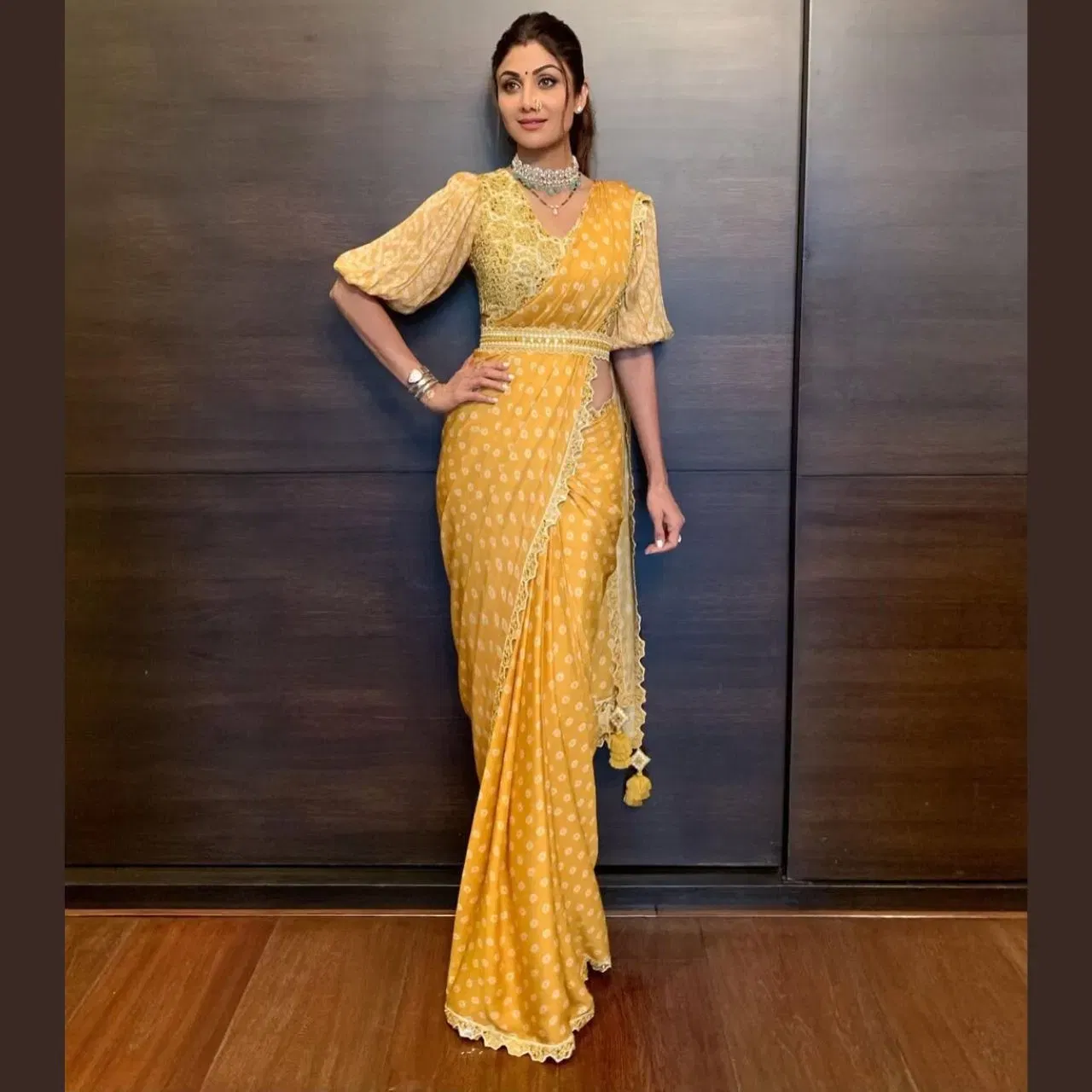ਸ਼ਿਲਪਾ ਸ਼ੈੱਟੀ ਯੈਲੋ ਕਲਰ ਦੀ ਬੰਧੇਜ ਪ੍ਰਿੰਟ ਵਾਲੀ ਸਾੜੀ ਵਿੱਚ ਬਹੁਤ ਹੀ ਰੈਡੀਐਂਟ ਲੁੱਕ ਵਿੱਚ ਨਜਰ ਆ ਰਹੀ ਹੈ। ਵਾਈਟ ਪੋਲਕਾ ਡੌਟ ਡਿਜ਼ਾਈਨ ਅਤੇ ਲਾਈ ਵੇਟ ਬਾਰਡਰ ਉਨ੍ਹਾਂ ਦੇ ਲੁੱਕ ਵਿੱਚ ਐਲੀਗੈਂਸ ਐਡ ਕਰ ਰਿਹਾ ਹੈ। ਥ੍ਰੀ ਕੁਆਟਰ ਲੈਂਥ ਵਾਲੀ ਪੱਫੀ ਸਲੀਵਜ਼ ਵਾਲਾ ਐਂਬੇਲਿਸ਼ਡ ਬਲਾਊਜ਼ ਲੁੱਕ ਨੂੰ ਰਿੱਚ ਬਣਾ ਰਿਹਾ ਹੈ। ਐਕਟ੍ਰੈਸ ਨੇ ਆਪਣੇ ਲੁੱਕ ਨੂੰ ਚੋਕਰ, ਸਟੱਡਸ, ਮਹਾਰਾਸ਼ਟਰੀਅਨ ਰੱਥ, ਮੰਗਲਸੂਤਰ ਅਤੇ ਕਫ਼ ਬਰੇਸਲੇਟ ਨਾਲ ਕੰਪਲੀਟ ਕੀਤਾ ਹੈ। ਉਨ੍ਹਾਂ ਦਾ ਇਹ ਐਥਨਿਕ ਲੁੱਕ ਗ੍ਰੇਸਫੁੱਲ ਸਟਾਈਲ ਅਤੇ ਟਾਈਮਲੈਸ ਫੈਸ਼ਨ ਸੈੰ, ਨੂੰ ਦਰਸਾਉਂਦਾ ਹੈ।