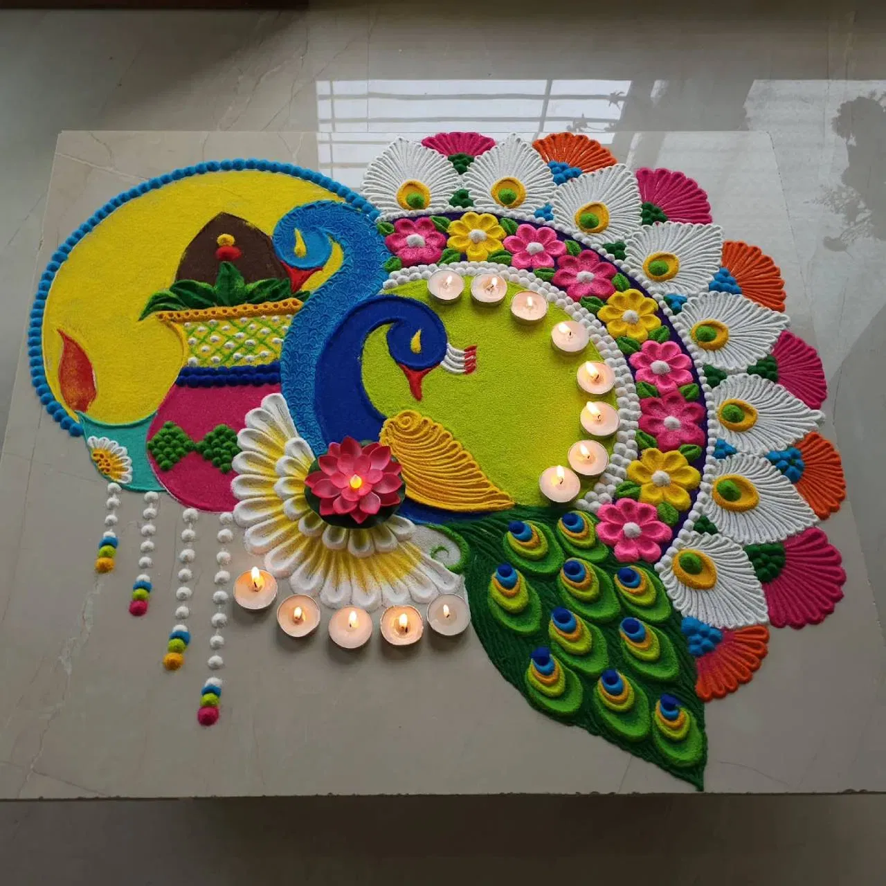 ਇਹ ਰੰਗੋਲੀ ਡਿਜ਼ਾਈਨ ਵੀ ਬੇਹੱਦ ਖੂਬਸੂਰਤ ਹੈ। ਇਸ ਵਿੱਚ ਦੋ ਮੋਰ ਬਣਾਏ ਗਏ ਹਨ। ਇੱਕ ਪਾਸੇ ਗੋਲ ਡਿਜ਼ਾਈਨ ਵਿੱਚ ਦੀਵਾ, ਝਾਲਰ ਅਤੇ ਕਲਸ਼ ਬਣਾਇਆ ਗਿਆ ਹੈ, ਜਦਕਿ ਦੂਜੇ ਪਾਸੇ ਮੋਰ ਦੇ ਪੰਖ, ਫੁੱਲ ਅਤੇ ਪੱਤੀਆਂ ਨਾਲ ਬਾਹਰਲੀ ਰਿੰਗ ਸਜਾਈ ਗਈ ਹੈ। ਰੰਗੋਲੀ ਦੇ ਅੰਦਰ ਤੇ ਬਾਹਰ ਮੋਮ ਦੇ ਦੀਏ ਰੱਖੇ ਗਏ ਹਨ, ਜਿਸ ਨਾਲ ਇਹ ਹੋਰ ਵੀ ਸੁੰਦਰ ਲੱਗਦਾ ਹੈ।