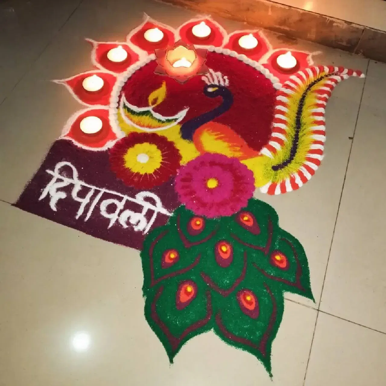 ਇਹ ਰੰਗੋਲੀ ਡਿਜ਼ਾਈਨ ਵੀ ਬੇਹੱਦ ਆਕਰਸ਼ਕ ਹੈ। ਇਸ ਵਿੱਚ ਮੋਰ ਦਾ ਚਿੱਤਰ ਬਣਾਕੇ ਆਲੇ ਦੁਆਲੇ ਗੋਲ ਘੇਰਾ ਬਣਾਇਆ ਗਿਆ ਹੈ, ਜਿਸ ਵਿੱਚ ਦੀਵੇ ਅਤੇ ਸਧਾਰਣ ਡਿਜ਼ਾਈਨ ਸ਼ਾਮਲ ਹਨ। ਨਾਲ ਹੀ ਫੁੱਲ ਅਤੇ ਮੋਰ ਦੇ ਖੰਭਾਂ ਦਾ ਡਿਜ਼ਾਈਨ ਵੀ ਜੋੜਿਆ ਗਿਆ ਹੈ। ਇੱਕ ਪਾਸੇ ਸਕਵੇਅਰ ਬਾਕਸ ਵਿੱਚ “ਦੀਵਾਲੀ” ਲਿਖਿਆ ਹੈ। ਤੁਸੀਂ ਵੀ ਇਸ ਤਰ੍ਹਾਂ ਦੀ ਰੰਗੋਲੀ ਆਸਾਨੀ ਨਾਲ ਬਣਾ ਕੇ ਆਪਣੇ ਘਰ ਦੀ ਸ਼ੋਭਾ ਵਧਾ ਸਕਦੇ ਹੋ।