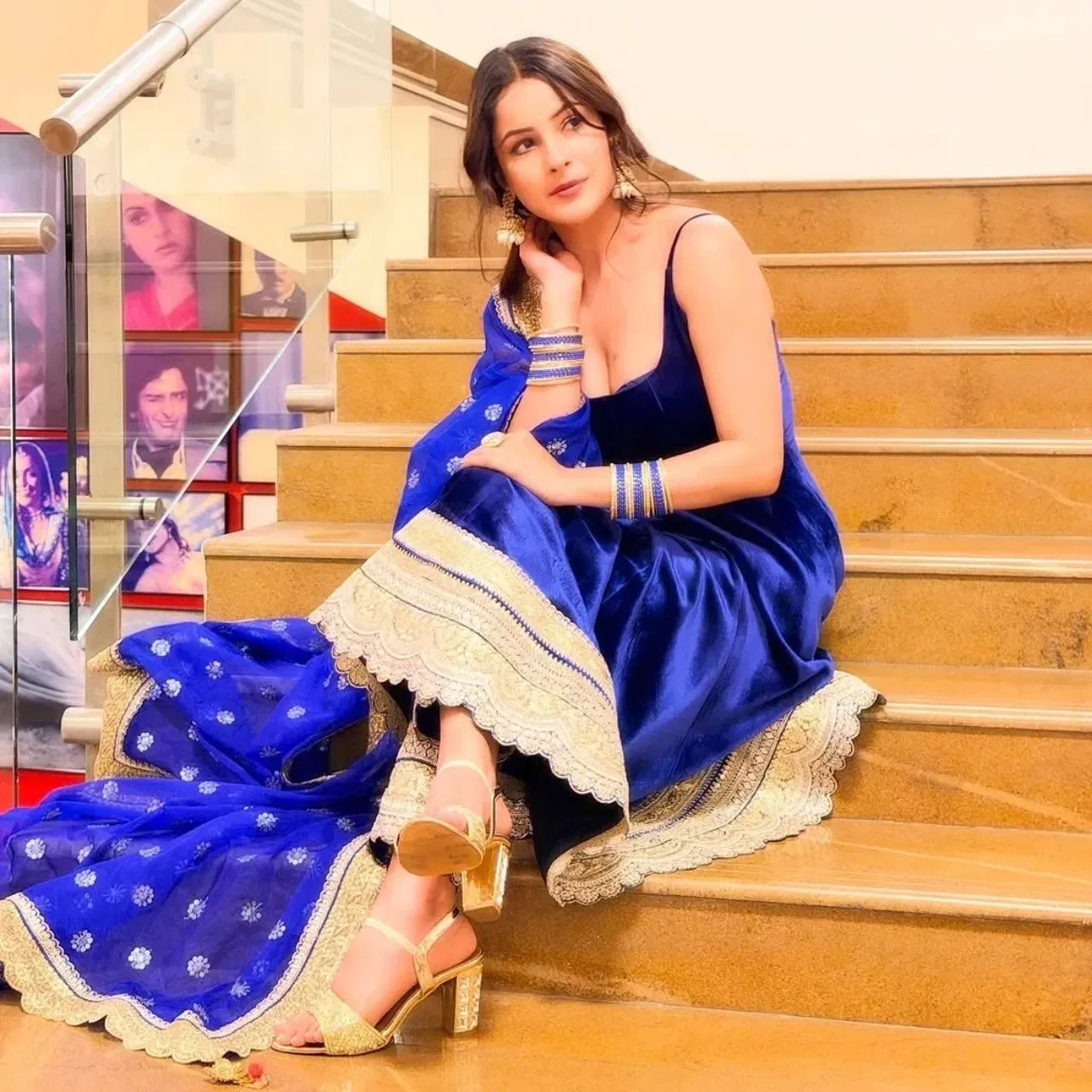 ਵੈਡਿੰਗ ਸੀਜਨ ਲਈ ਸ਼ਹਿਨਾਜ਼ ਗਿੱਲ ਦਾ ਇਹ ਲੁੱਕ ਰਿਕ੍ਰਿਏਟ ਕੀਤਾ ਜਾ ਸਕਦਾ ਹੈ। ਉਨ੍ਹਾਂ ਨੇ ਇੱਕ ਰਾਇਲ ਬਲੂ ਵੈਲਵੇਟ ਅਨਾਰਕਲੀ ਸੂਟ ਕੈਰੀ ਕੀਤਾ ਹੈ, ਜਿਸਦੇ ਹੇਠਾਂ ਇੱਕ ਹੈਵੀ ਲੇਸ ਬਾਰਡਰ ਤਿਆਰ ਕੀਤਾ ਗਿਆ ਹੈ, ਅਤੇ ਟ੍ਰਾਉਜਰ ਵਿੱਚ ਵੀ ਸੁੰਦਰ ਲੇਸ ਵਰਕ ਹੈ। ਗੋਲਡਨ ਬਾਰਡਰ ਨਾਲ ਮੇਲ ਖਾਂਦੀ ਹੀਲਸ ਉਨ੍ਹਾਂ ਦੇ ਲੁੱਕ ਵਿੱਚ ਇੱਕ ਰਿੱਚ ਅਪੀਲ ਦੇ ਰਹੀ ਹੈ। ਹਲਕਾ ਦੁਪੱਟਾ, ਮੈਚਿੰਗ ਚੂੜੀਆਂ ਅਤੇ ਪੋਲਕੀ ਝੁਮਕੇ ਉਨ੍ਹਾਂ ਦੇ ਲੁੱਕ ਨੂੰ ਕੰਪਲੀਟ ਕਰ ਰਹੇ ਹਨ।