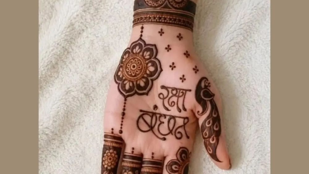 ਮਿਨੀਮਲਿਸਟਿਕ ਮਹਿੰਦੀ ਲਗਾਉਣੀ ਹੈ, ਜੋ ਸਿੰਪਲ ਵੀ ਹੋਵੇ ਅਤੇ ਦੇਖਣ ਵਿੱਚ ਖੂਬਸੂਰਤ ਲੱਗੇ ਤਾਂ ਇਸ ਡਿਜ਼ਾਈਨ ਤੋਂ ਆਈਡੀਆ ਲਓ। ਸਭ ਤੋਂ ਪਹਿਲਾਂ ਕਲਾਈ ਵਾਲਾ ਪੈਟਰਨ ਪੂਰਾ ਕਰੋ। ਇਸ ਤੋਂ ਬਾਅਦ ਹਥੇਲੀ 'ਤੇ “Happy Raksha Bandhan” ਲਿਖੋ। ਫਿਰ ਉੱਪਰ ਵਾਲੇ ਹਿੱਸੇ ਵਿੱਚ ਇੱਕ ਫੁੱਲ ਬਣਾ ਲਓ। ਹੁਣ ਹਿਨਾ ਡ੍ਰਾਪ ਨਾਲ ਰਿੰਗ ਦੇ ਡਿਜ਼ਾਈਨ ਵਿੱਚ ਚੇਨ ਬਣਾਓ। ਇਸ ਤੋਂ ਬਾਅਦ ਪੂਰੇ ਹੱਥ 'ਤੇ 5 ਡ੍ਰਾਪ ਵਾਲੇ ਬੂਟੇ ਬਣਾਕੇ ਉਂਗਲਾਂ ਦਾ ਡਿਜ਼ਾਈਨ ਪੂਰਾ ਕਰ ਲਓ। (Image: zeenat_mehandi_desingn)
